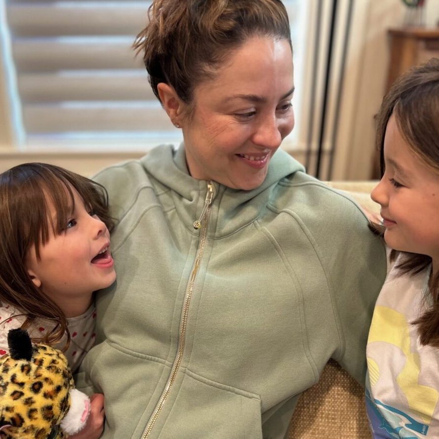 Young happy mom connecting with her two young daughters